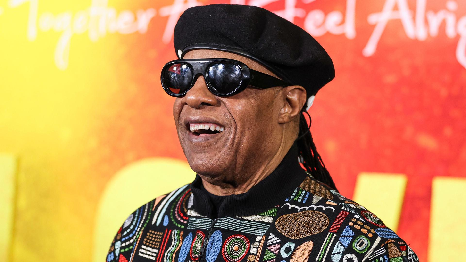 Stevie Wonder lächelt vor einer bunten Wand bei der Premiere des Films "Bob Marley: One Love" in Los Angeles.