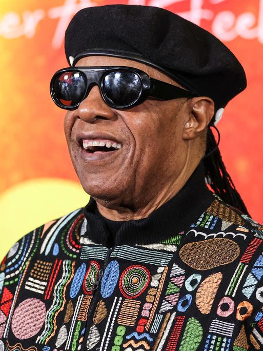 Stevie Wonder lächelt vor einer bunten Wand bei der Premiere des Films "Bob Marley: One Love" in Los Angeles. 