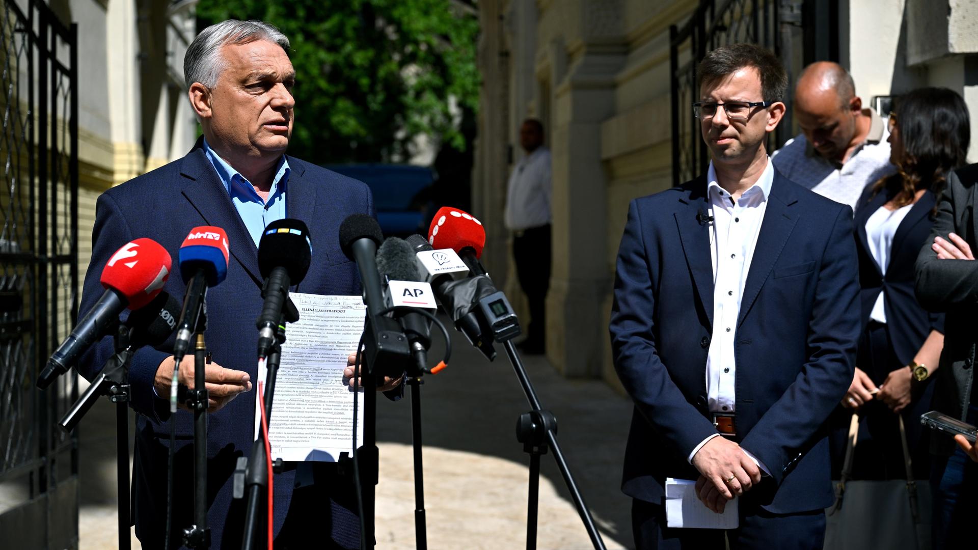 Viktor Orbán steht vor Mikrofonen und spicht.