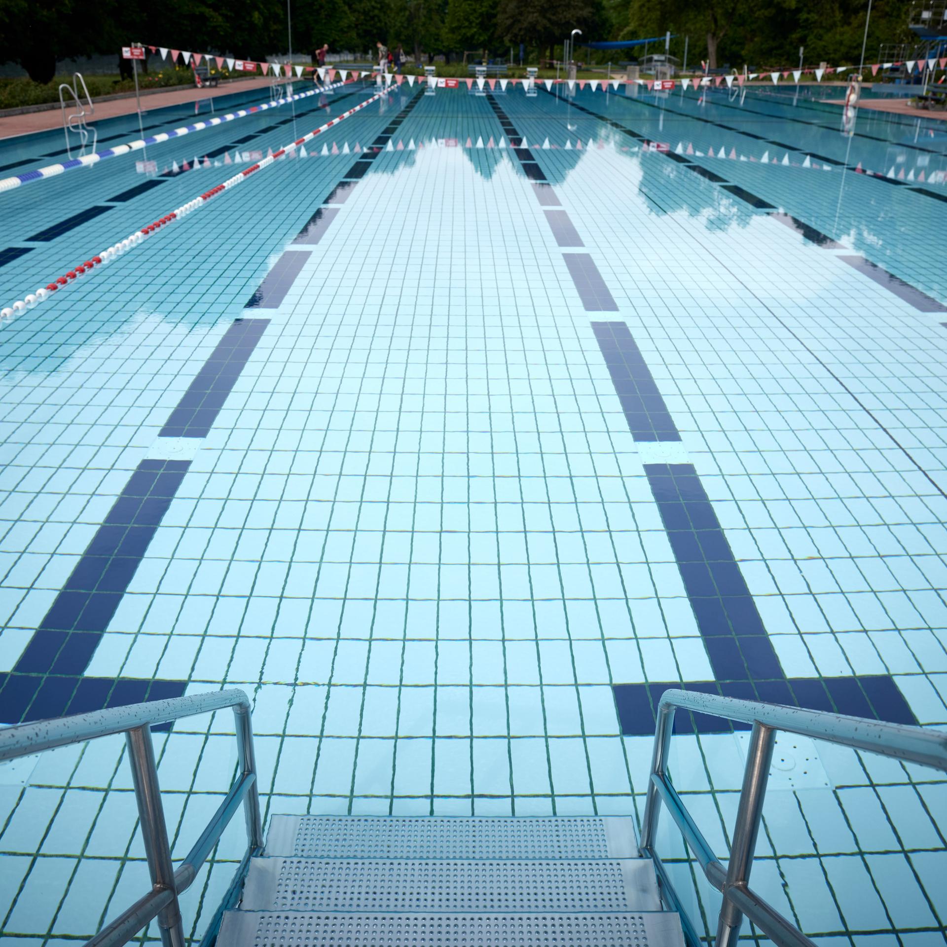 Blick in einen Außenpool eines Schwimmbades in Deutschland. Die verschiedenen Bahnen des Pools sind im Wasser gut zu erkennen.