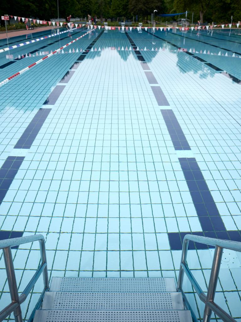 Blick in einen Außenpool eines Schwimmbades in Deutschland. Die verschiedenen Bahnen des Pools sind im Wasser gut zu erkennen.