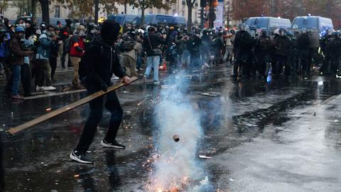 Ein Demonstrant steht mit einer Holzlatte in den Händen vor einer Polizeikette (Foto vom 24.10.2026). 