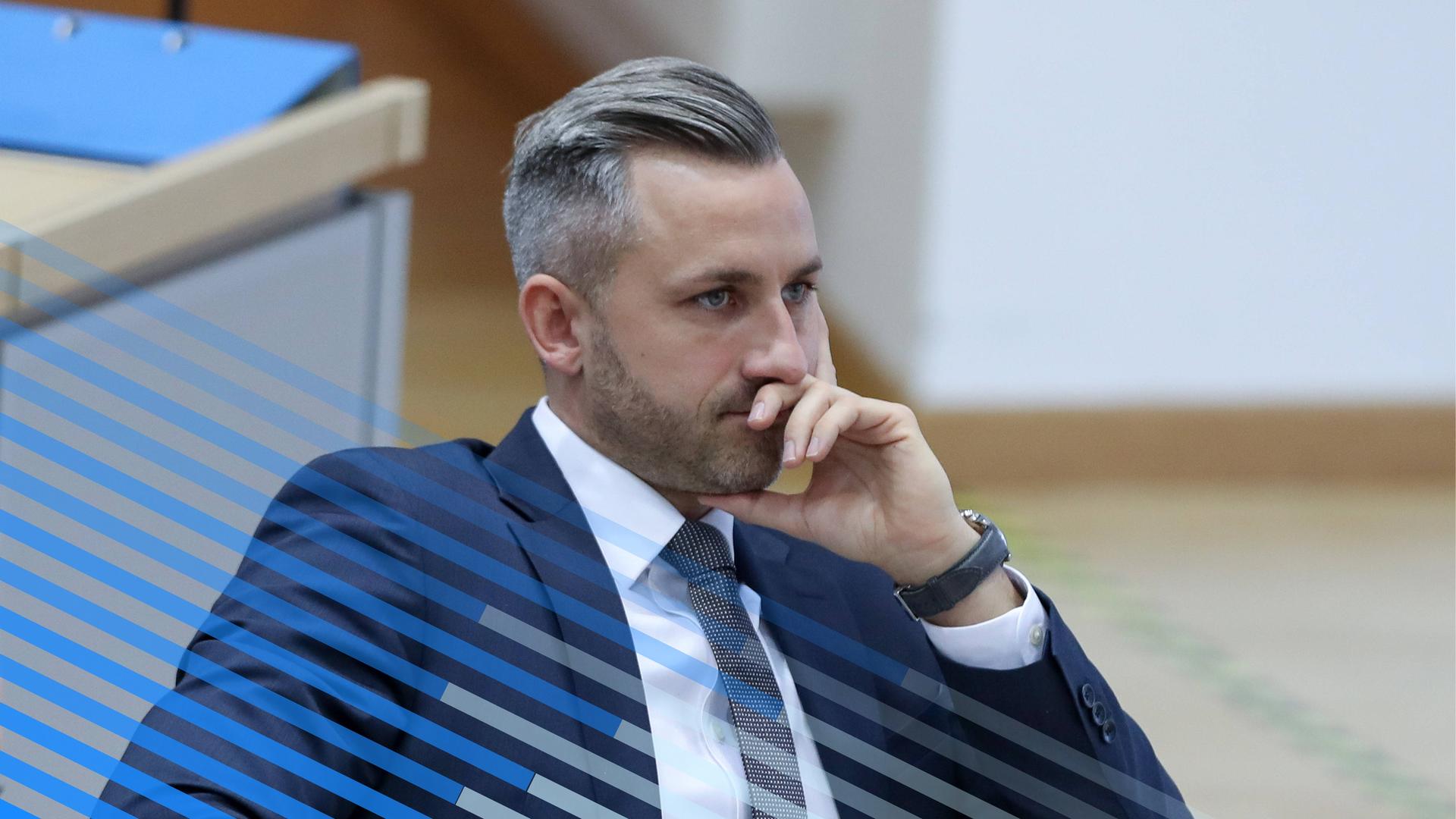 Ulrich Siegmund sitzt im Landtag Sachsen-Anhalt, sein Kopf ist auf seine Hand gestützt, er trägt Anzug und Krawatte.