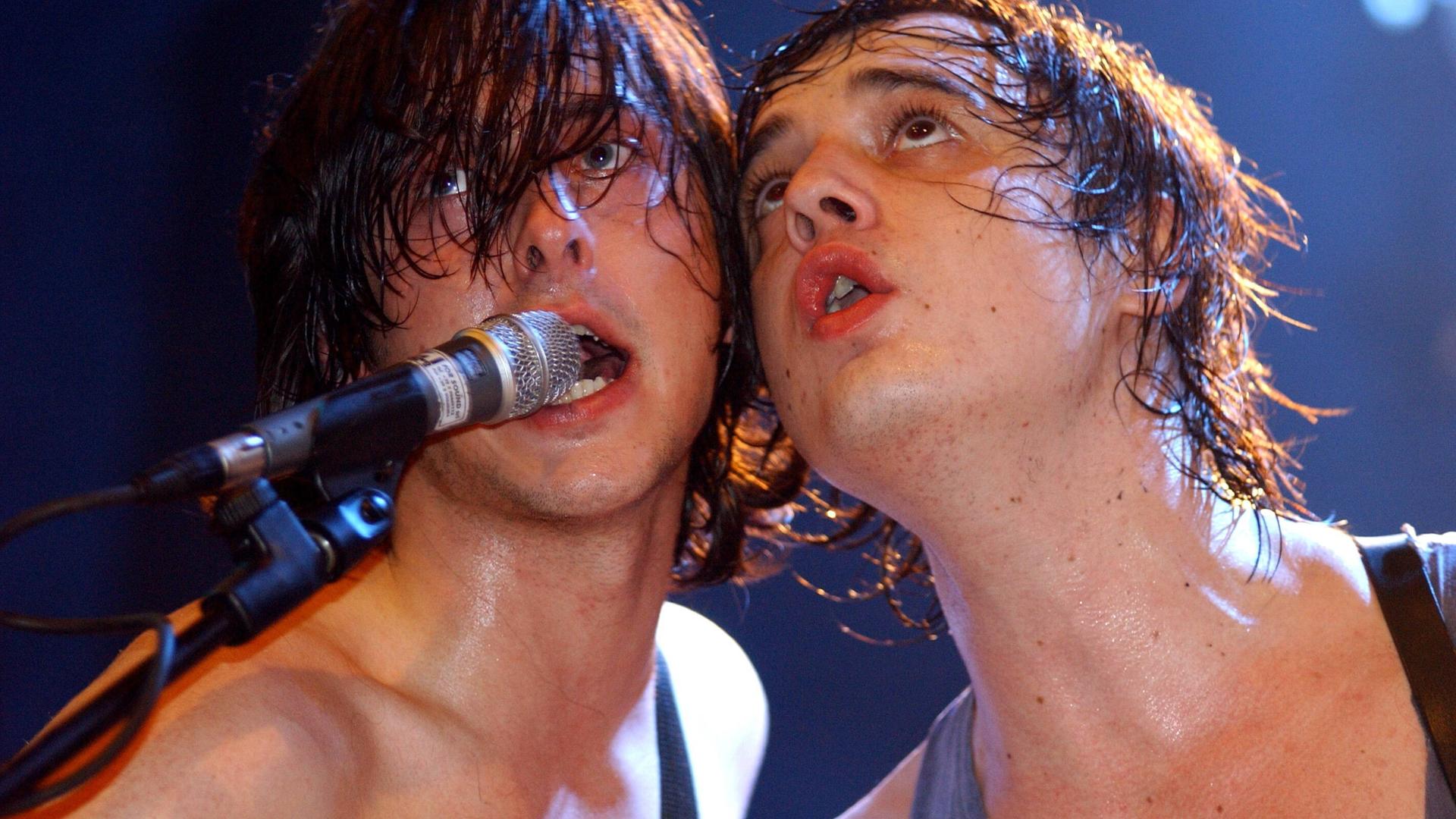 Die britische Indie-Rock-Band The Libertines – Sänger und Frontman Pete Doherty (r) und Carl Barât – bei einem Konzert: Die beiden singen mit schweißnassen Haaren in ein Mikrofon. 