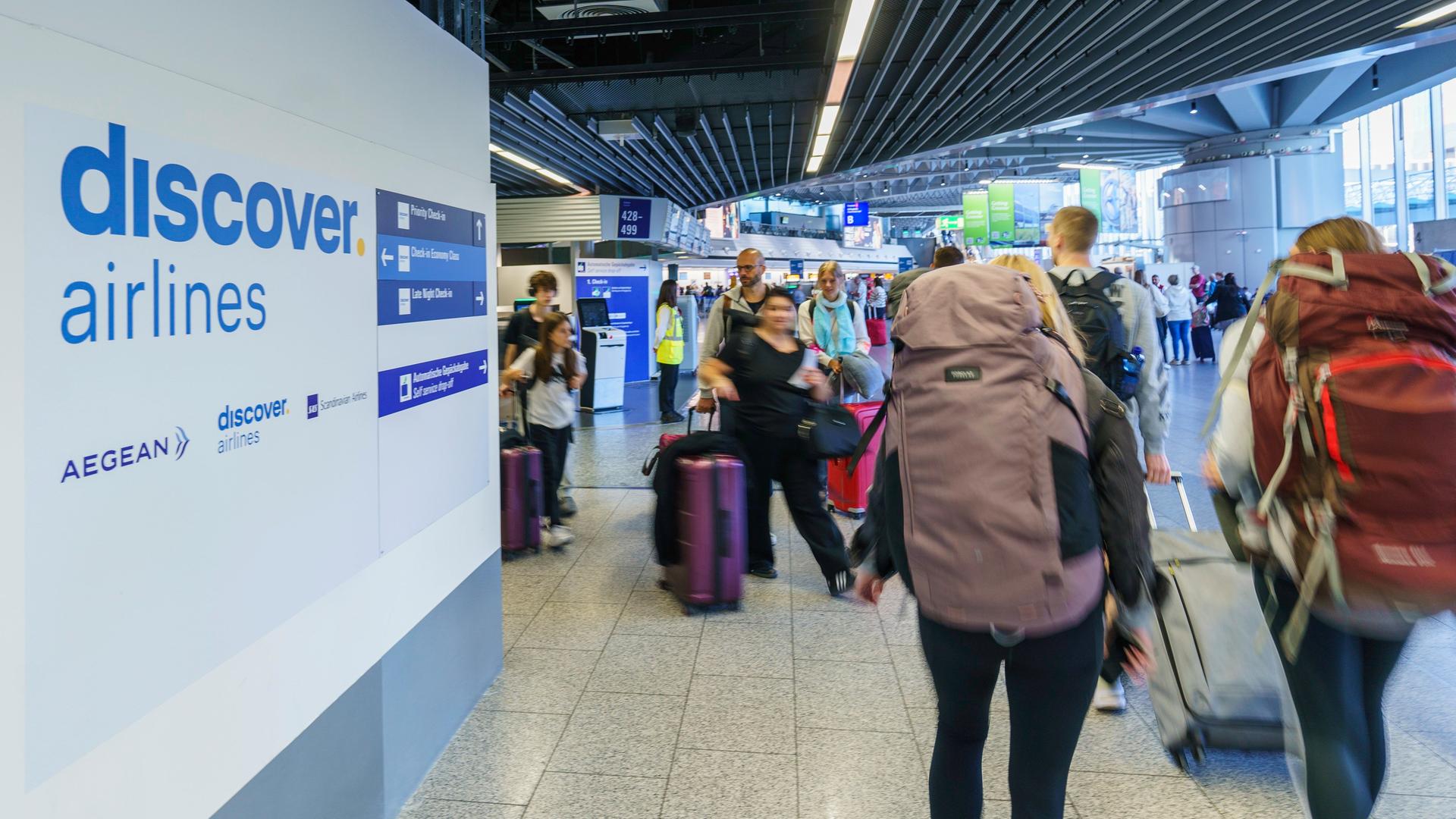 Frankfurt/Main: Reisende gehen am Rhein-Main-Flughafen zum Check-in an den Schaltern von Discover Airlines vorbei. 