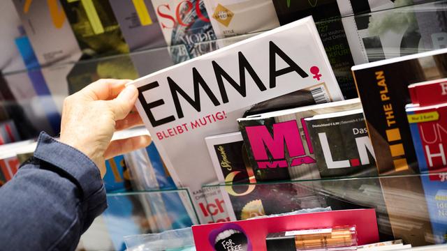 Eine Hand zieht die Zeitschrift "Emma" aus einem Zeitschriften-Ständer.