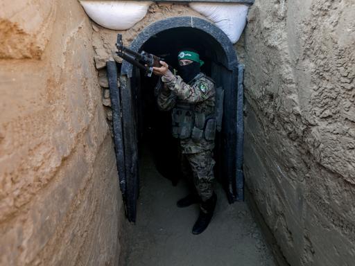 Ein Hamas-Kämpfer hält ein Maschinengewehr aus einem Tunnelzugang heraus. 