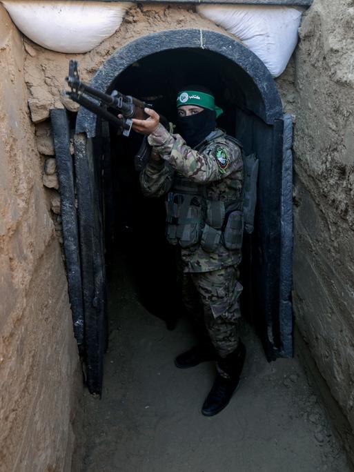 Ein Hamas-Kämpfer hält ein Maschinengewehr aus einem Tunnelzugang heraus. 
