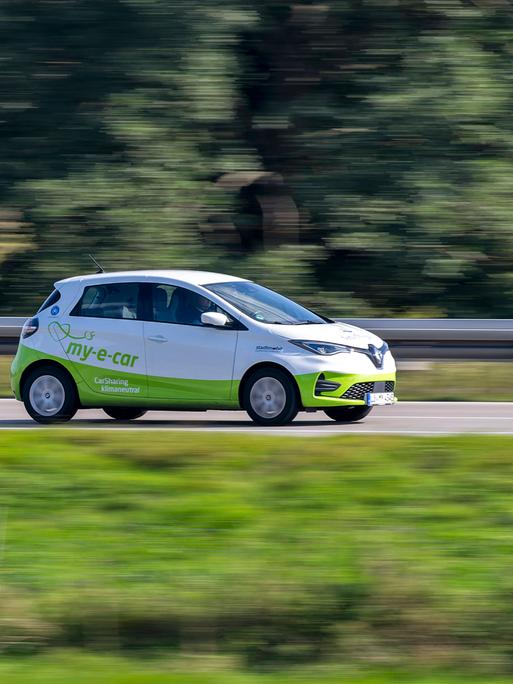 Ein Auto in voller Fahrt. Es fährt zum rechten Bildrand. Bewegungsunschärfe deutet die Bewegung des Fahrzeugs an. Ein Auto in voller Fahrt. Es fährt zum rechten Bildrand. Bewegungsunschärfe deutet die Bewegung des Fahrzeugs an.