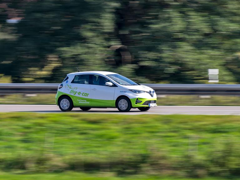 Ein Auto in voller Fahrt. Es fährt zum rechten Bildrand. Bewegungsunschärfe deutet die Bewegung des Fahrzeugs an. Ein Auto in voller Fahrt. Es fährt zum rechten Bildrand. Bewegungsunschärfe deutet die Bewegung des Fahrzeugs an.