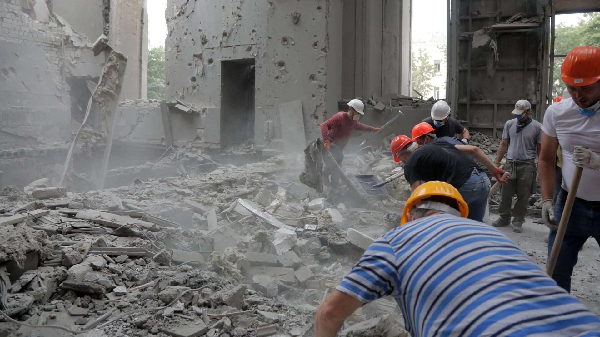 Arbeiter entfernen Trümmer aus dem Innern eines Gebäudes.