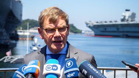 Außenminister Johann Wadephul (CDU) gibt auf dem Stützpunkt der 7. US-Flotte ein Statement. Im Hintergrund stehen das Kommandoschiff USS Blue Ridge (l), rechts das Schiff HMS Prince of Wales der Royal Navy.