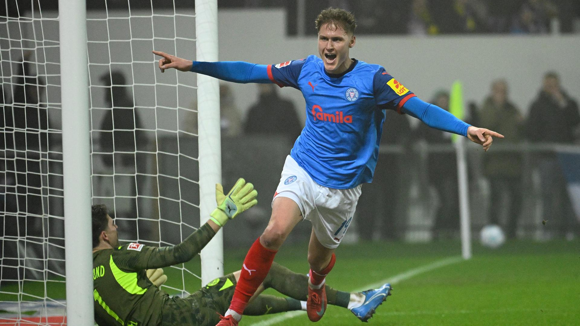 Ein Fußballspieler in einem blauen Trikot jubelt.