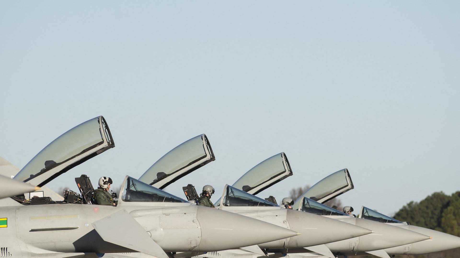 Mehrere Eurofighter-Kampfflugzeuge der britischen Armee stehen nebeneinander. Die Cockpits der Flugzeuge sind geöffnet. Die Piloten sitzen in ihren Maschinen.