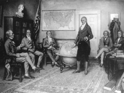 In dem Gemälde des Malers Clyde Deland sieht man eine Sitzung des US-amerikanischen Kabinetts im Jahr 1822. In der Mitte steht der damalige US-Präsident James Monroe. Die Diskussion über die Außenpolitik wird als Geburtsstunde der Monroe-Doktrin angesehen. 