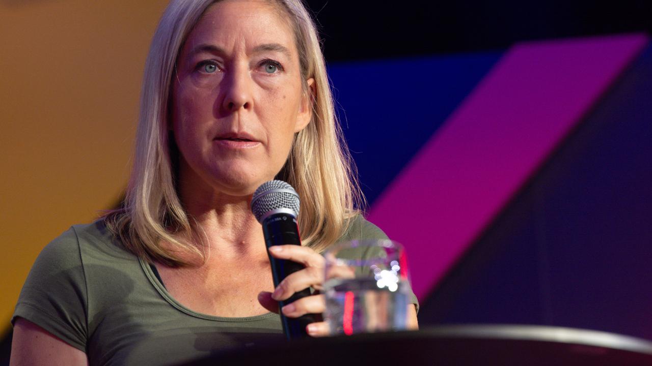 Blonde Frau mit langen Haaren spicht in ein Mikrofon.