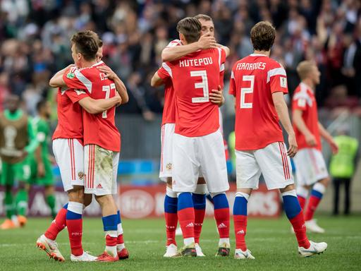 Spieler der russischen Nationalmannschaft im roten Trikots umarmen sich.
