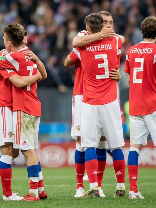 Spieler der russischen Nationalmannschaft im roten Trikots umarmen sich.