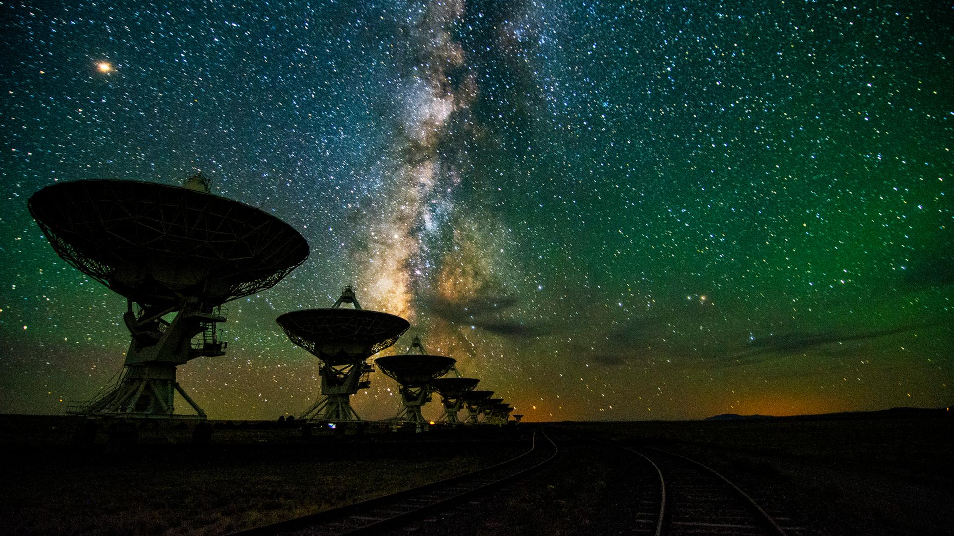 Eine Reihe von Teleskopen vor dem nächtlichen Sternenhimmel
