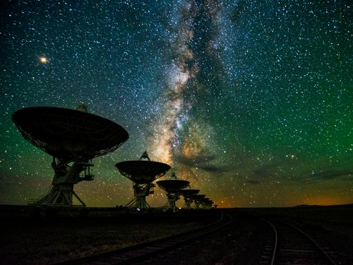 Eine Reihe von Teleskopen vor dem nächtlichen Sternenhimmel