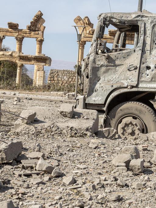 Ein ausgebrannter Lkw steht vor den Ruinen der antiken Tempelanlage Baalbek im Libanon.