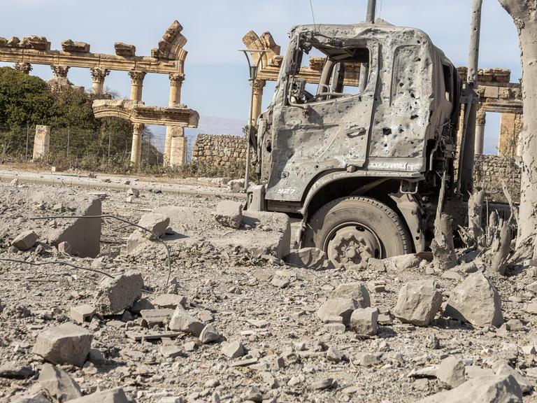 Ein ausgebrannter Lkw steht vor den Ruinen der antiken Tempelanlage Baalbek im Libanon.