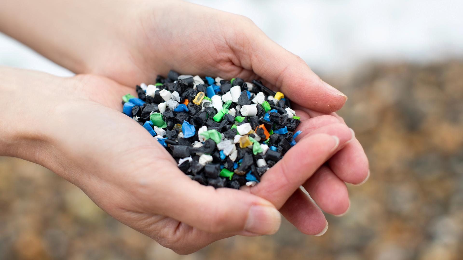 Nahaufnahme zweier Hände, die buntes Plastikgranulat halten Nahaufnahme zweier Hände, die buntes Plastikgranulat halten