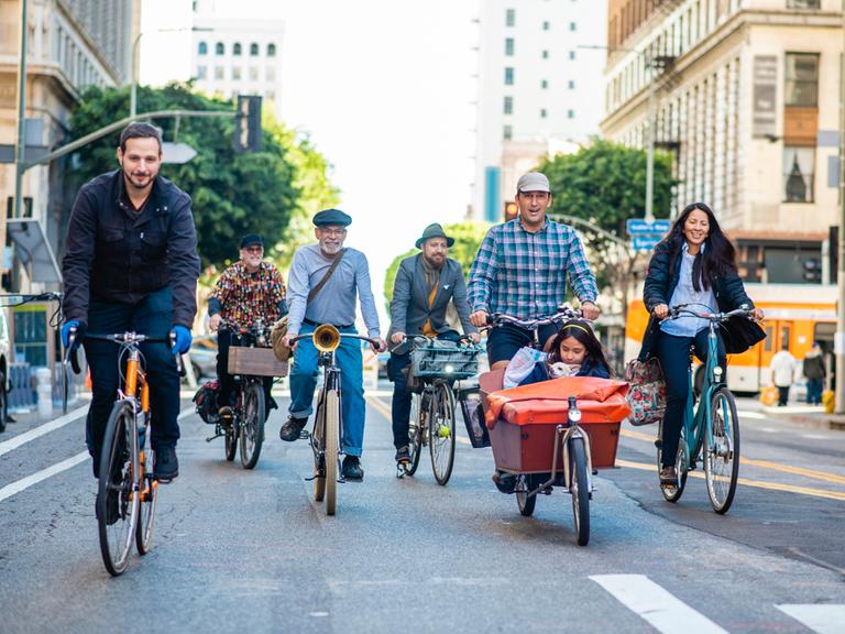 Fahrradfahrerinnen und Lastenradfahrer mit Kind und Hund auf einer Straße in Downtown Los Angeles.