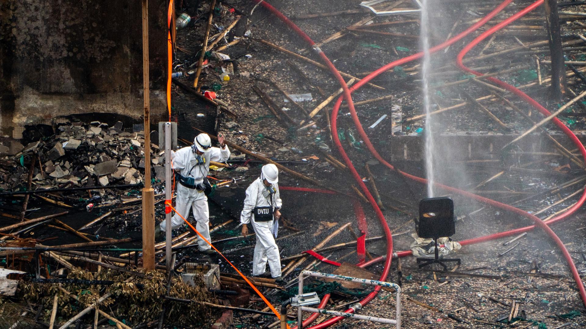 Polizeibeamte in Schutzanzügen inspizieren nach einem tödlichen Brand im Wohnkomplex Wang Fuk Court in Tai Po die Brandstelle. 