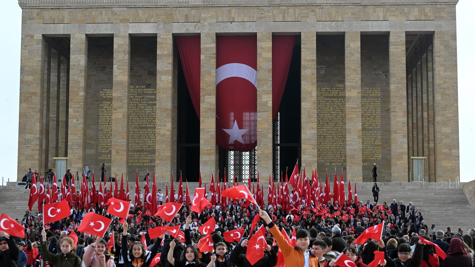 Kinder besuchen das Mausoleum des Gründers der Türkischen Republik, Mustafa Kemal Atatürk. Sie schwenken kleine türkische Fahnen, am Mausoleum hängt eine große Nationalflagge.