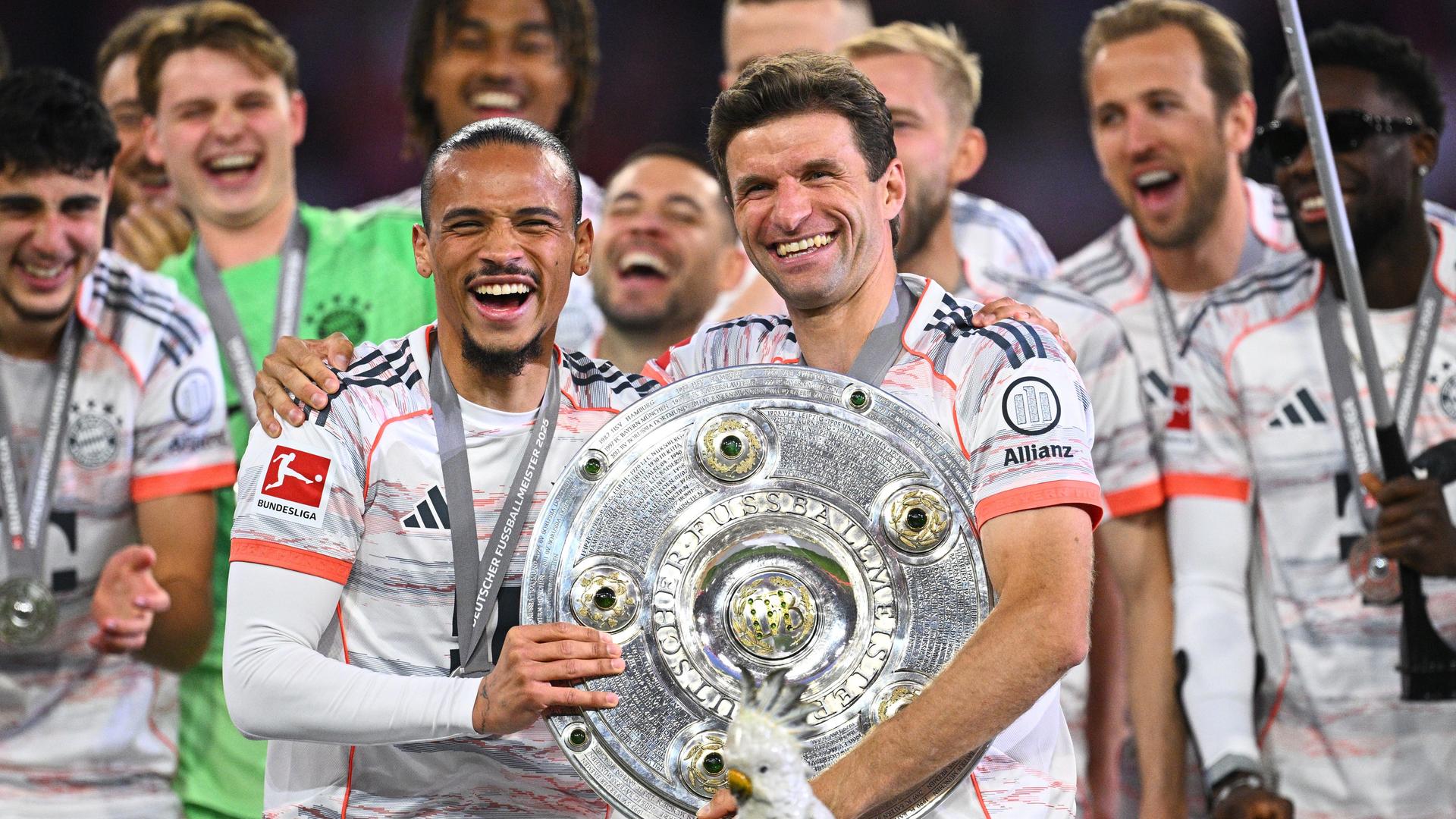 Leroy Sane (l) und Thomas Müller lachen. Sie haben die Meister-Schale in den Händen. Leroy Sane (l) und Thomas Müller lachen. Sie haben die Meister-Schale in den Händen.