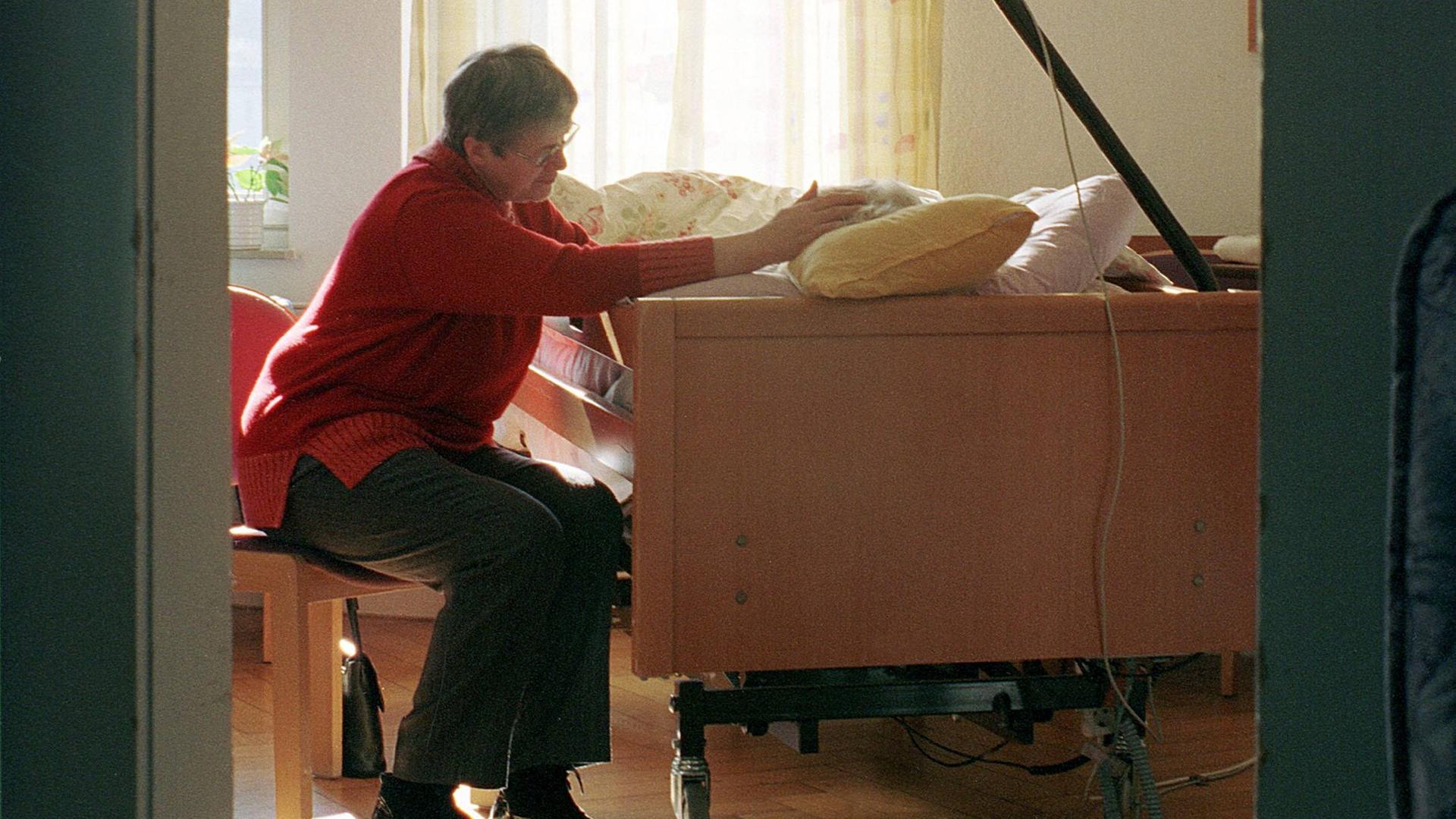 Eine ältere Frau besucht ihre Freundin, die in einem Pflegebett liegt in einem Hospiz in Stuttgart.
