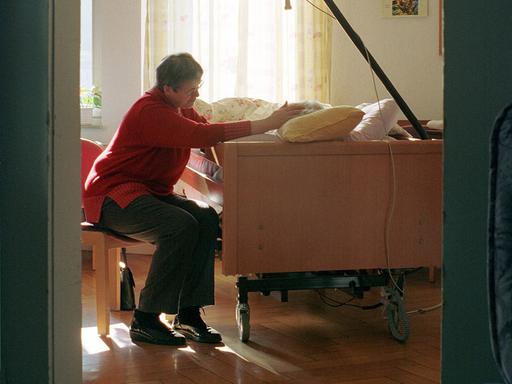 Eine ältere Frau besucht ihre Freundin, die in einem Pflegebett liegt in einem Hospiz in Stuttgart.