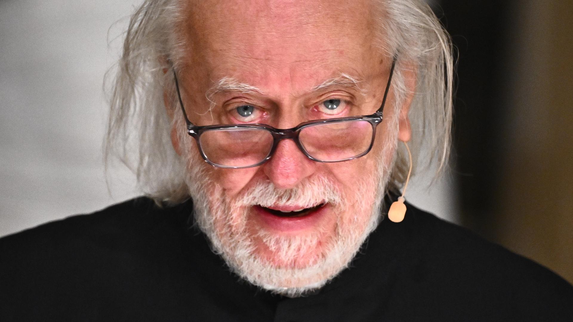 László Krasznahorkai, Literaturnobelpreisträger 2025, hält seiner Dankesrede in der Schwedischen Akademie in Stockholm. Er trägt eine schwarz umrandete Brillen und eine schwarze Jacke.