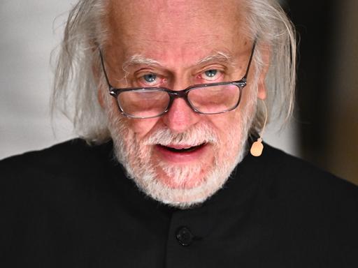 László Krasznahorkai, Literaturnobelpreisträger 2025, hält seiner Dankesrede in der Schwedischen Akademie in Stockholm. Er trägt eine schwarz umrandete Brillen und eine schwarze Jacke.