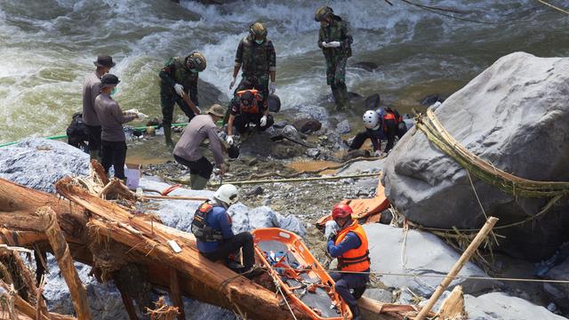 Rettungskräfte stehen an einem Fluss in Indonesien. Sie suchen nach Flutopfern.