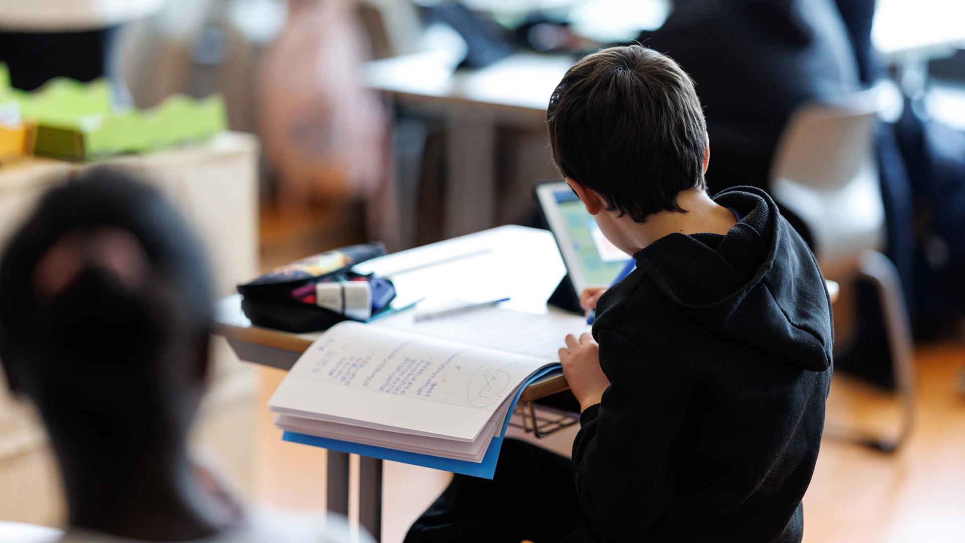 Ein Schüler bearbeitet mit Hilfe von seinem Tablet ein Aufgabenblatt.