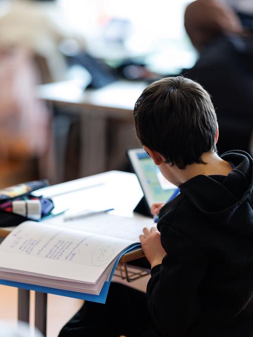 Ein Schüler bearbeitet mit Hilfe von seinem Tablet ein Aufgabenblatt. Ein Schüler bearbeitet mit Hilfe von seinem Tablet ein Aufgabenblatt.