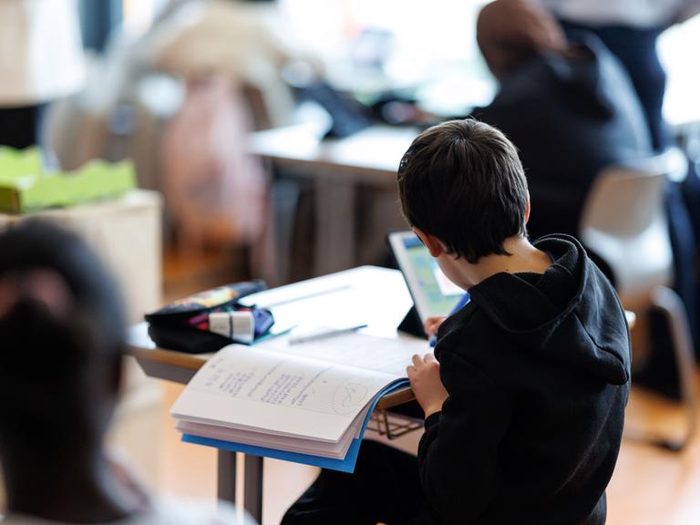 Ein Schüler bearbeitet mit Hilfe von seinem Tablet ein Aufgabenblatt. Ein Schüler bearbeitet mit Hilfe von seinem Tablet ein Aufgabenblatt.