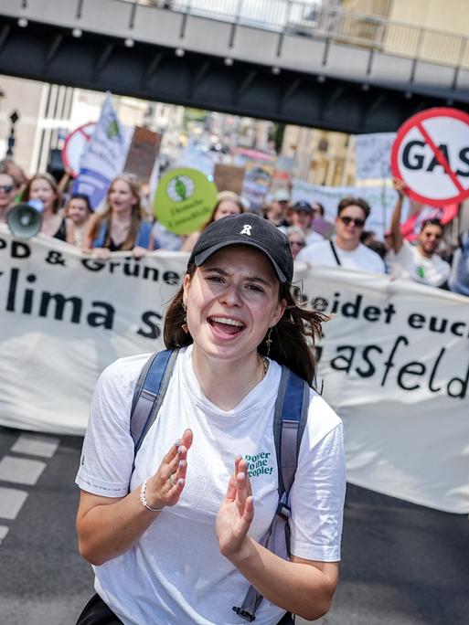 Luisa Neubauer läuft über eine Straße in Berlin, hinter ihr halten Klimaaktivisten ein Banner hoch.