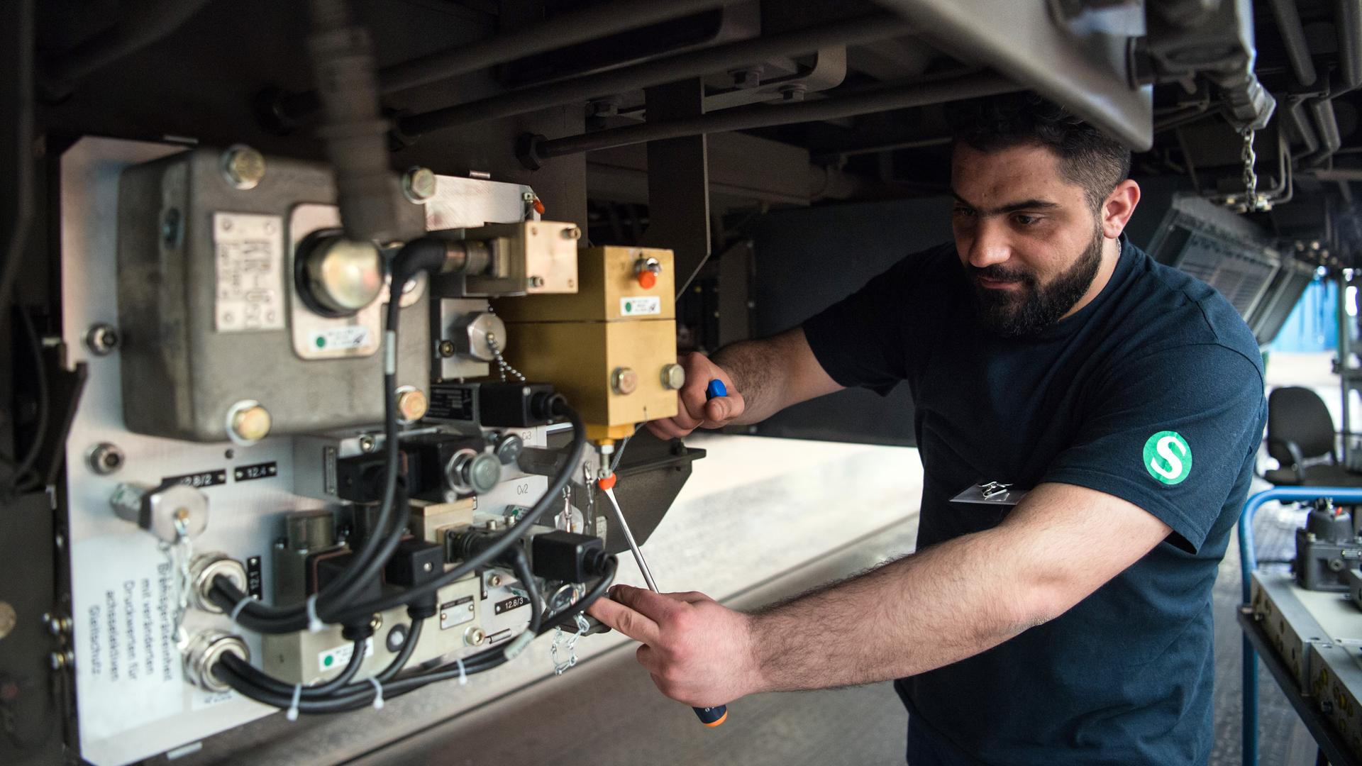 Ein Syrer arbeitet bei der Deutschen Bahn im Werk Berlin-Schöneweide an einer Bremsgeräteeinheit. 