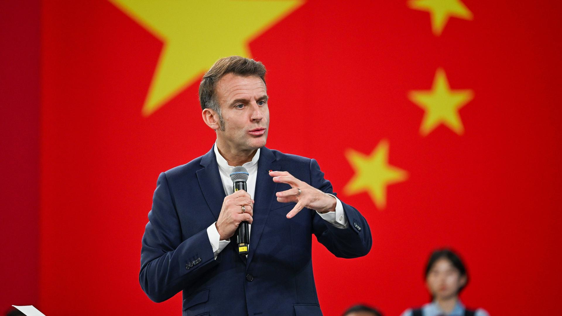 Frankreichs Präsident Emmanuel Macron spricht vor Studenten bei einem China-Besuch. Hinter ihm ist die chinesische Landesflagge. 
