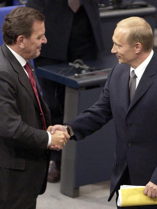 Zwei Mäner stehen in Anzügen im Reichstagsgebäude: Der russische Präsident Wladimir Putin (r.) wird am 25.9.2001 bei seinem Eintreffen zu einer Sondersitzung des Bundestages von Bundeskanzler Gerhard Schröder (SPD) begrüßt.
