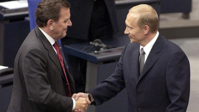 Zwei Mäner stehen in Anzügen im Reichstagsgebäude: Der russische Präsident Wladimir Putin (r.) wird am 25.9.2001 bei seinem Eintreffen zu einer Sondersitzung des Bundestages von Bundeskanzler Gerhard Schröder (SPD) begrüßt.