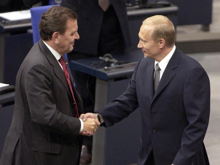 Zwei Mäner stehen in Anzügen im Reichstagsgebäude: Der russische Präsident Wladimir Putin (r.) wird am 25.9.2001 bei seinem Eintreffen zu einer Sondersitzung des Bundestages von Bundeskanzler Gerhard Schröder (SPD) begrüßt.