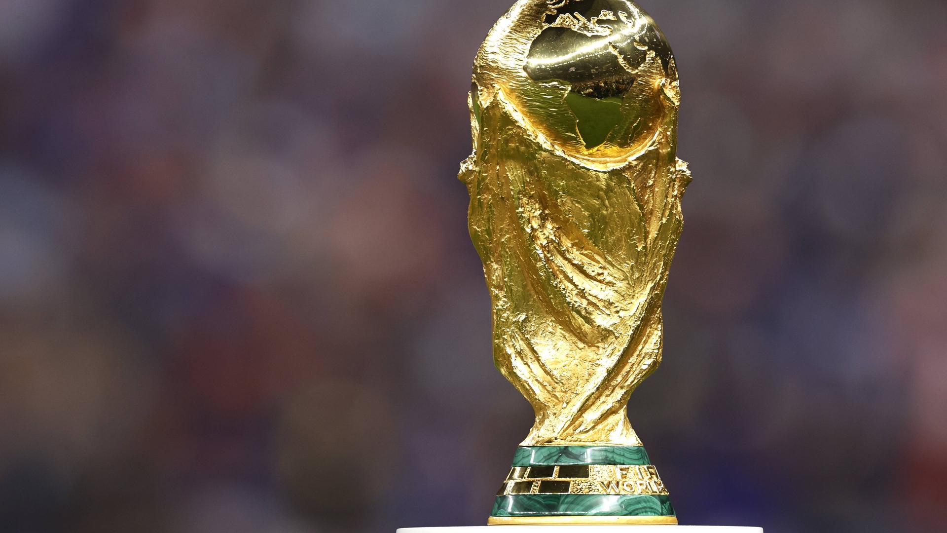 Der goldene WM-Pokal steht auf einem Podest in einem Fußballstadion.