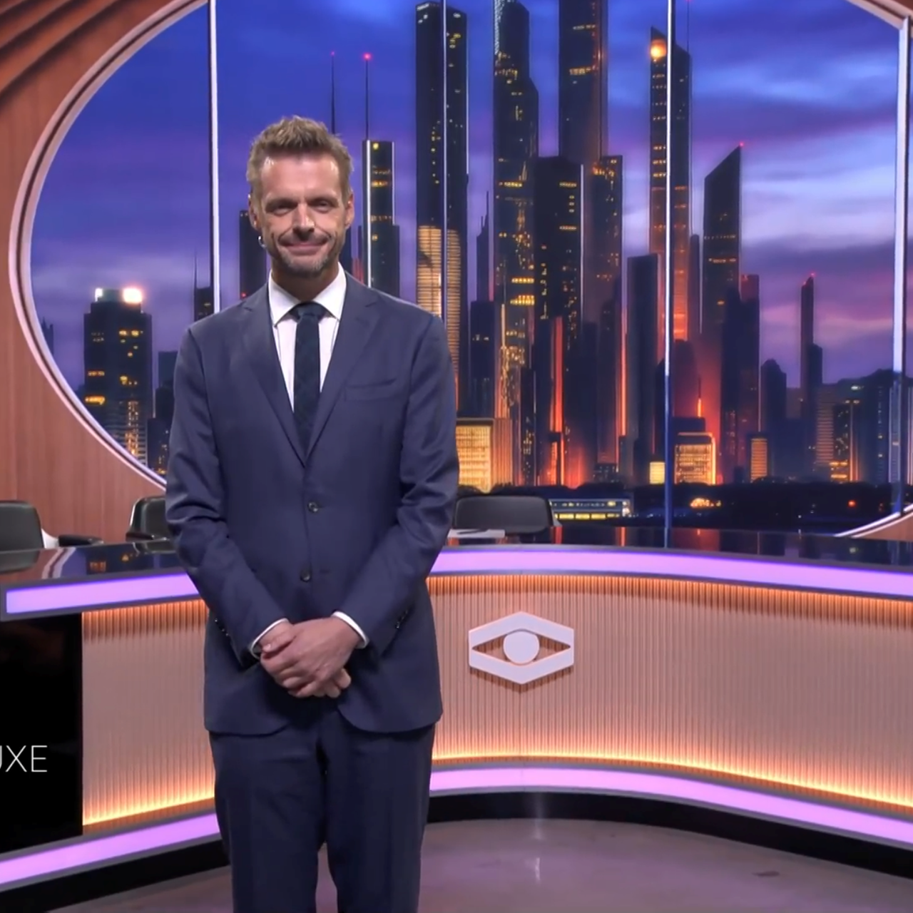 Moderator Florian Schroeder steht zu Beginn der ersten Ausgabe vom ZDF Journal Deluxe mit gefalteten Händen im Studio.