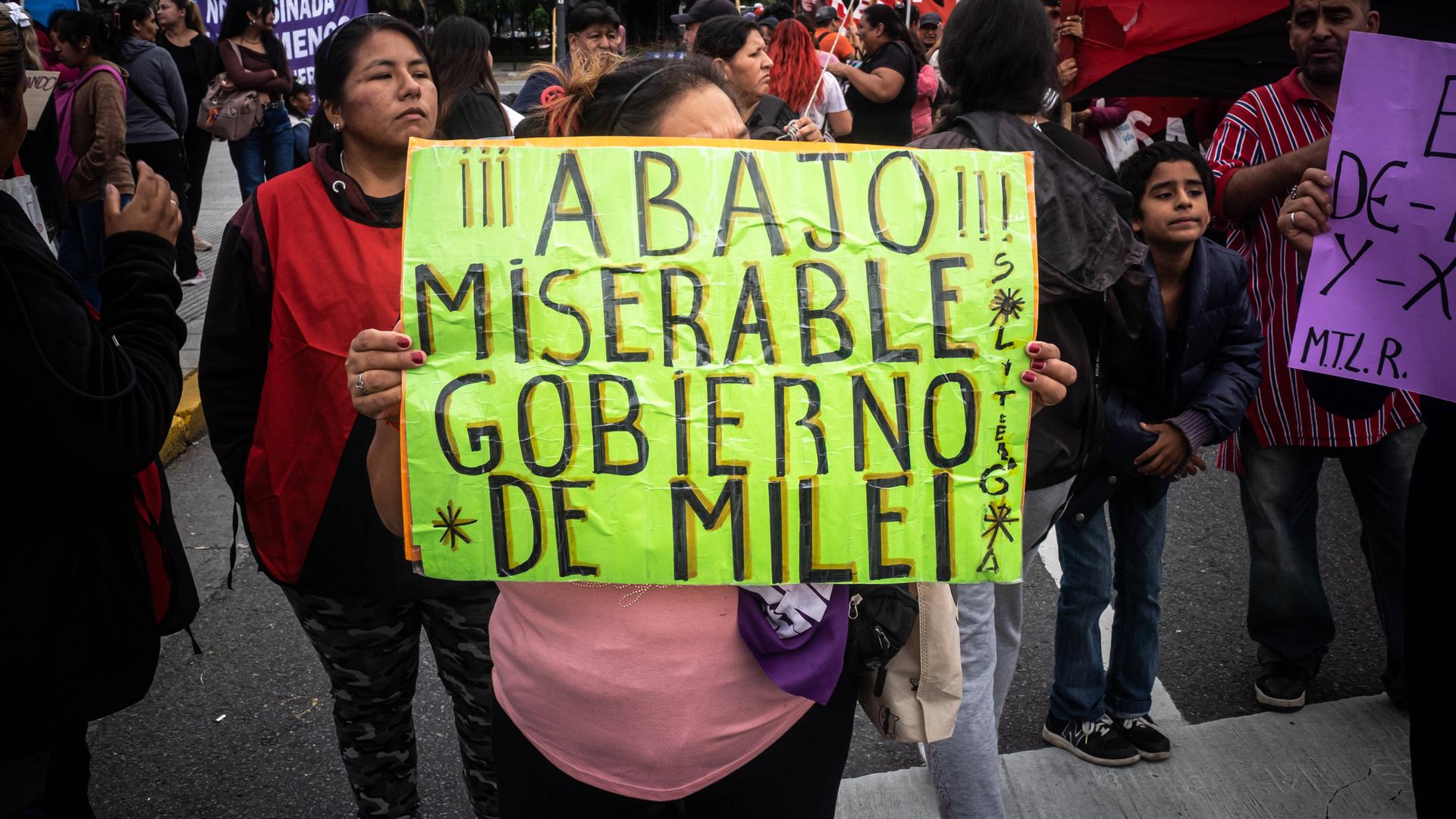 In Buenos Aires hebt eine Frau bei einer Demonstration ein Schild hoch, auf dem sie die Regierung von Präsident Milei kritisiert.