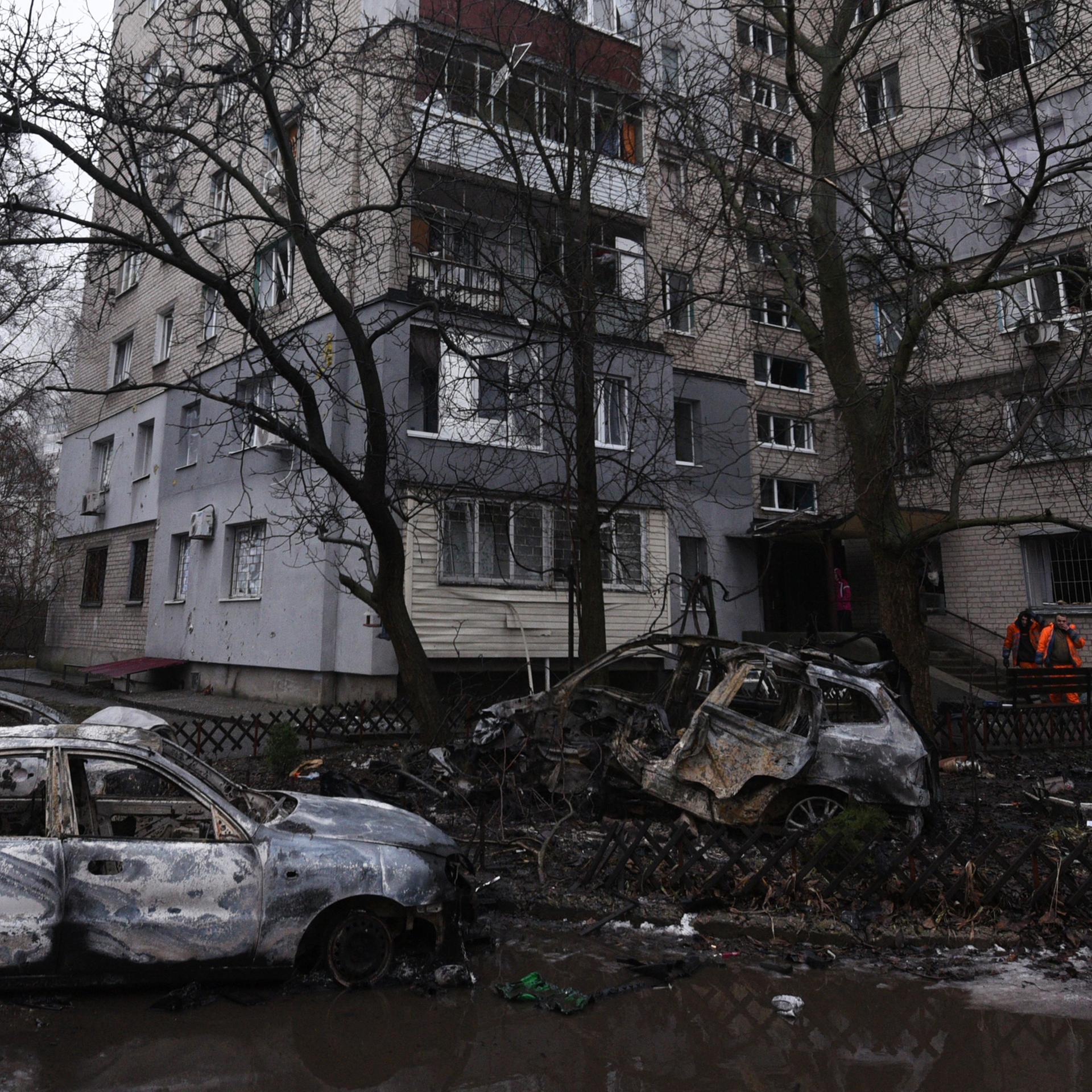 Trümmer im Innenhof eines beschädigten Wohngebäudes neben zerstörten Autos nach einem russischen Drohnenangriff im ukrainischen Dnipro am 7. Januar 2026.
