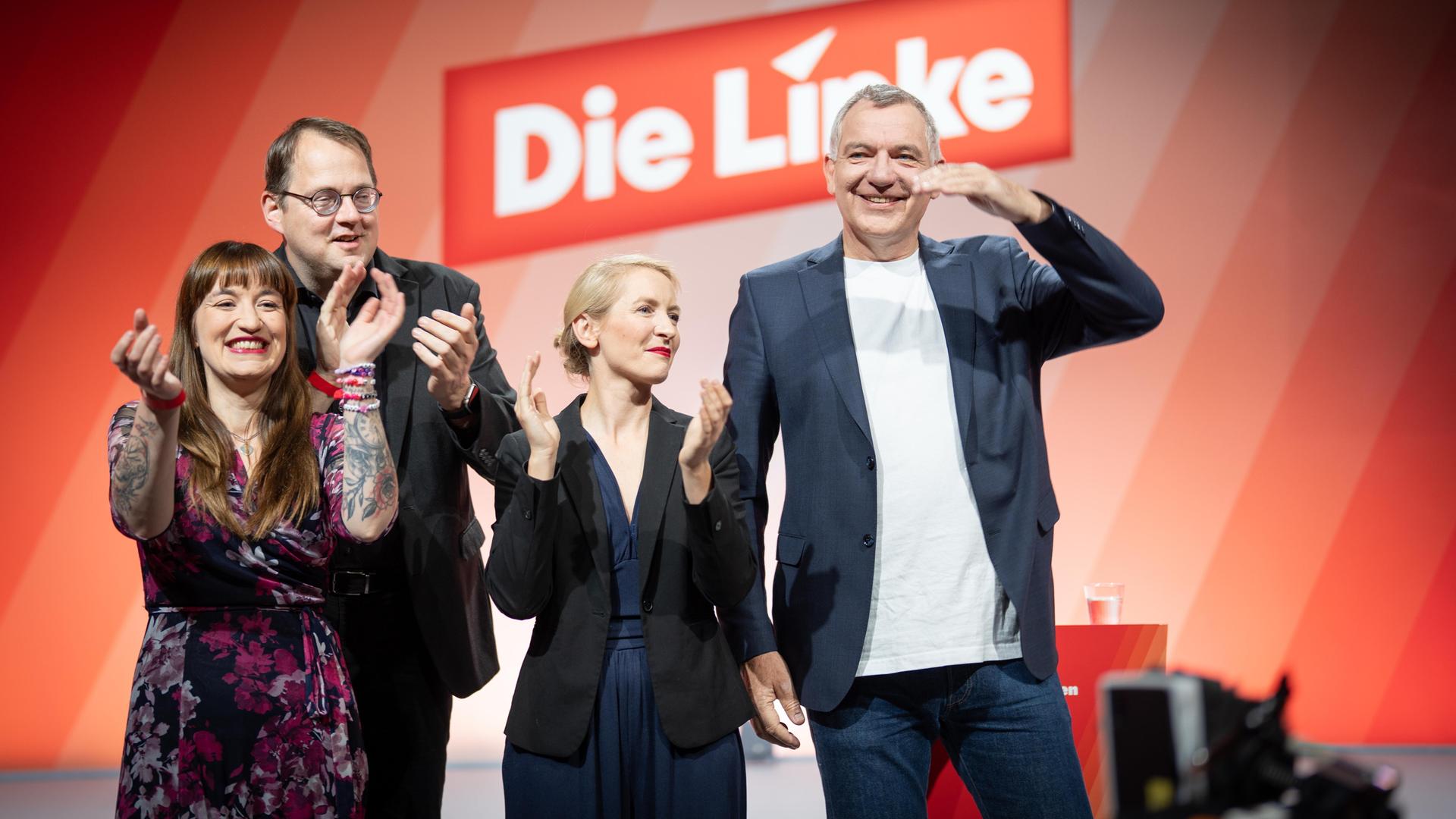Die Linken-Politiker Heidi Reichinnek, Sören Pellmannn, Ines Schwerdtner und Jan van Aken (von links). Sie wirken ausgelassen, im Hintergrund ist auf roter Wand das Logo der Partei Die Linke zu sehen. 